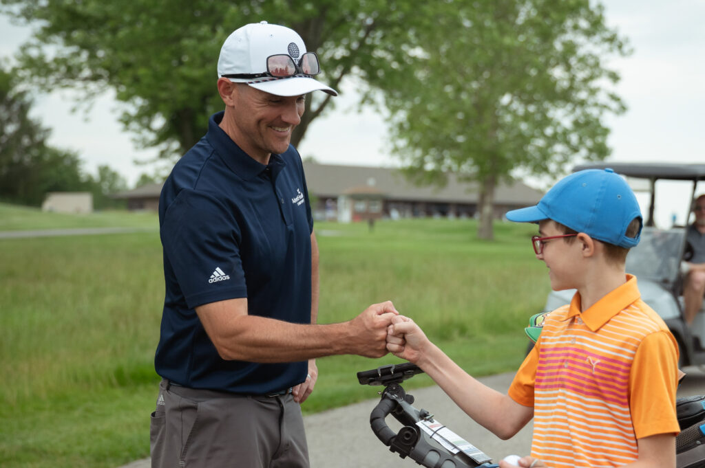 Watson Links adult golf mentor fist bumping a junior golfer while playing in a free round funded by Watson Links programming.